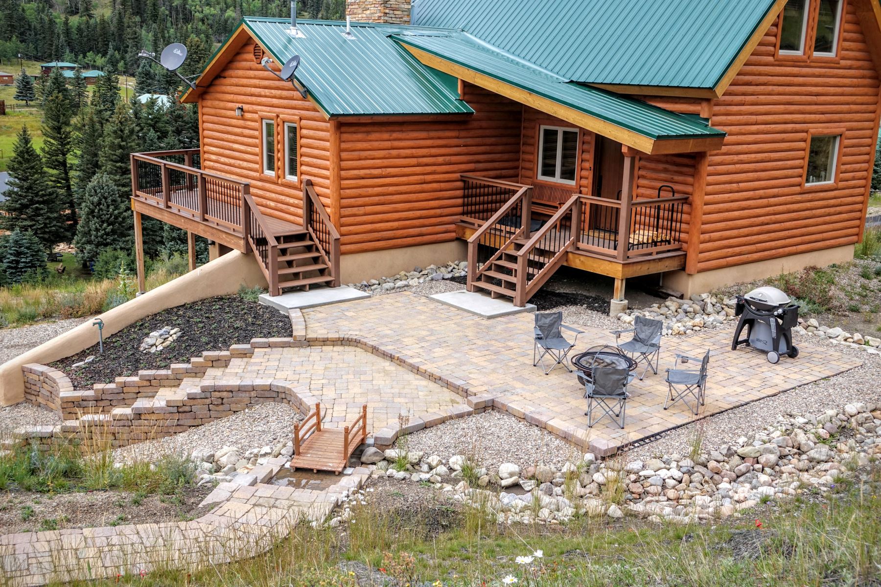 View of the back of the property, complete with beautiful stonework, a fire pit, grill, and your own private hot tub