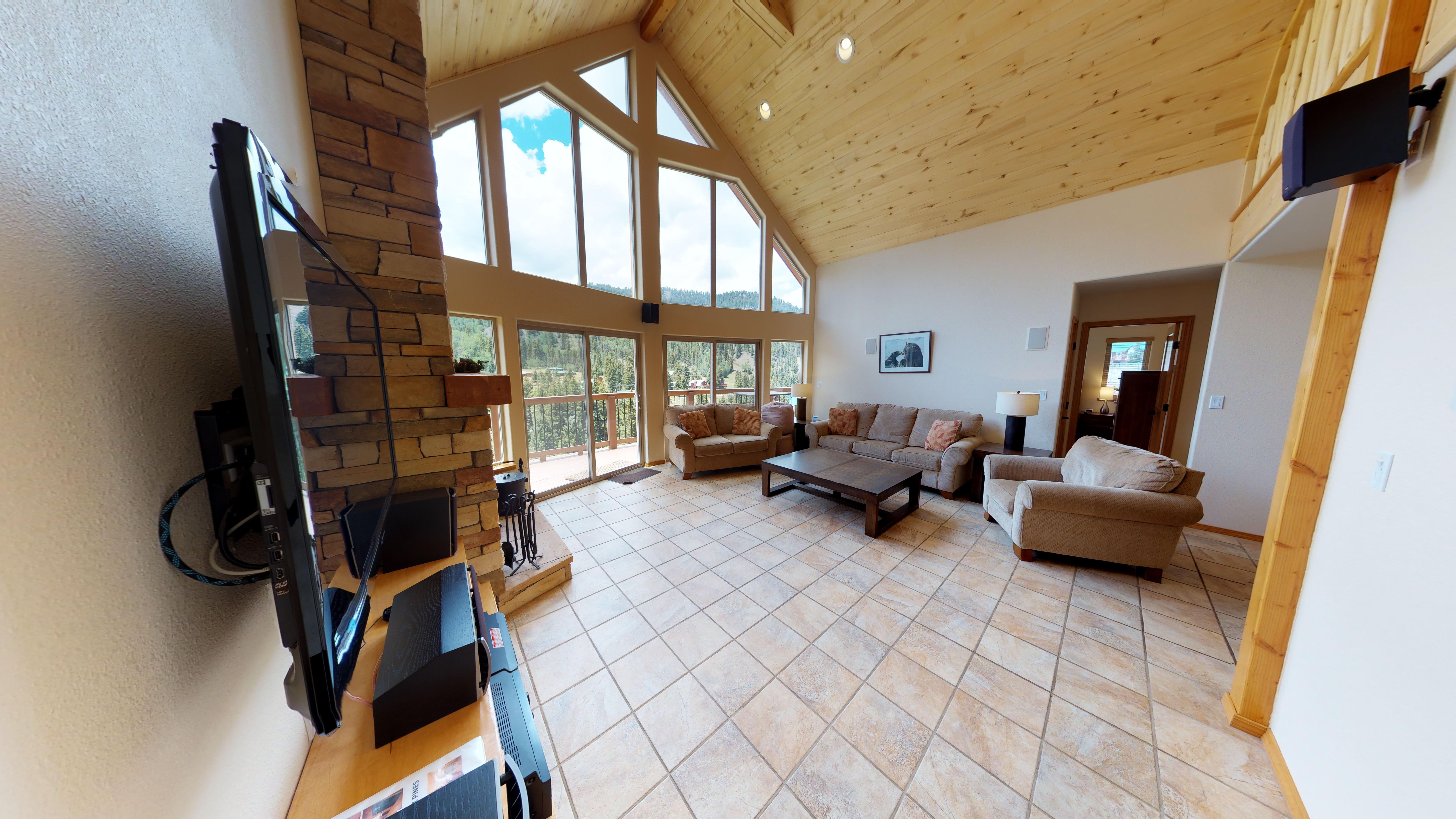 Living room and entertainment center, with floor to ceiling windows that overlook the mountains