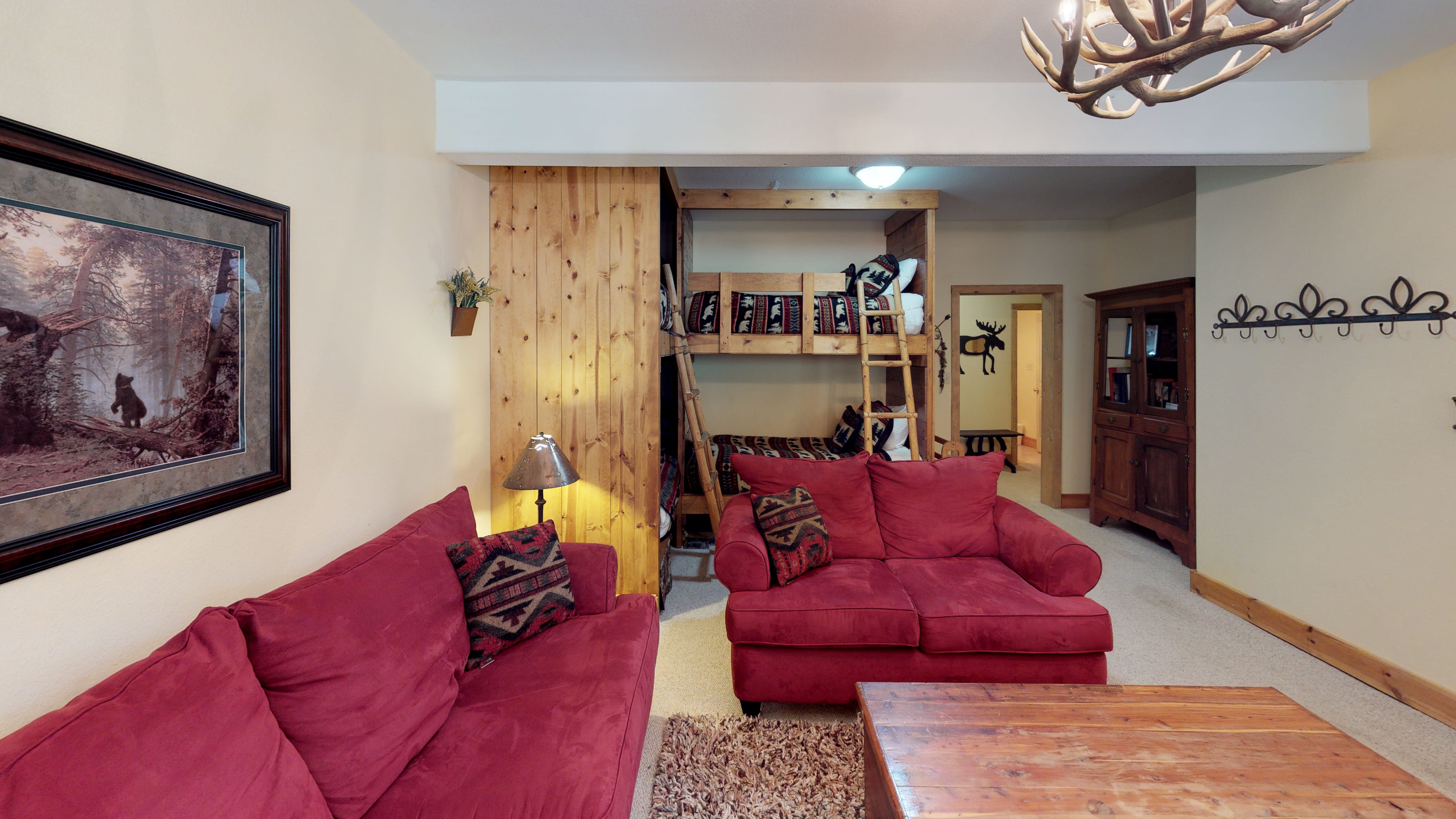 View from seating area with 2 bunk beds, leading to bedroom with queen bed and bathroom